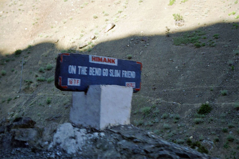 road sign: on the bend go slow friend