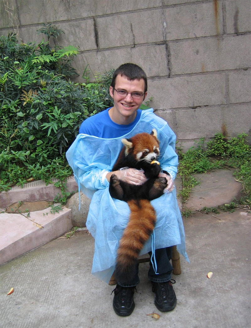 a man is holding red panda on his knees